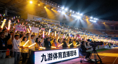 体育场夜晚灯光璀璨，球迷看台助威，九游体育直播现场